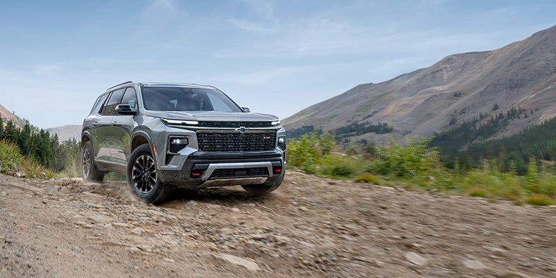 Chevrolet Traverse driving off-road on a rocky mountain trail with a scenic landscape in the background